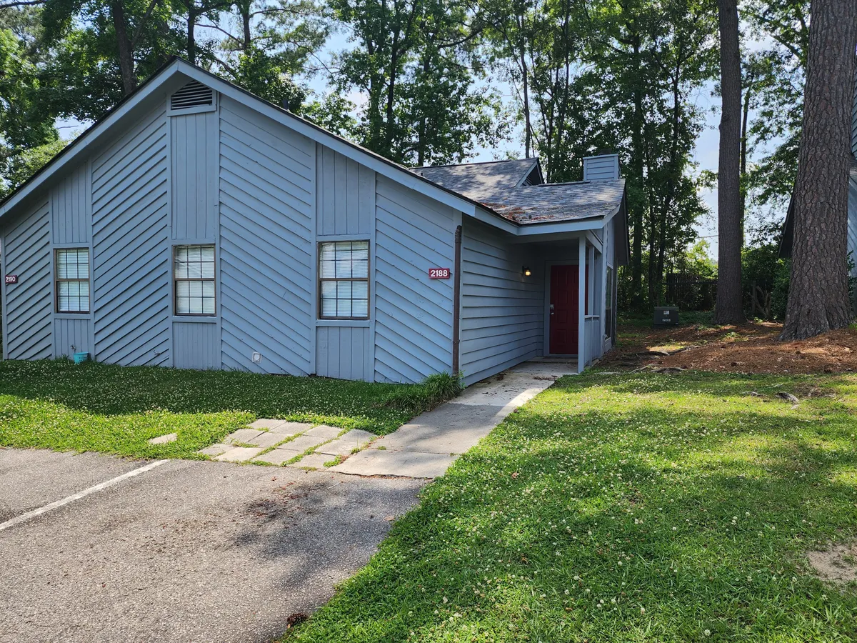 This image showcases the front exterior of the condo, featuring welcoming blue siding, a bold red door, and a pathway leading to the entrance. The inviting porch hints at relaxing outdoor moments, suggesting a safe and pleasant environment for families arriving for their stay.