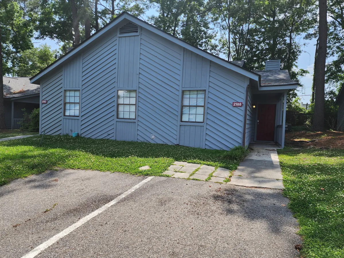 This image shows the blue exterior of the house with a red front door, complemented by a well-maintained lawn and a welcoming porch. The front door is prominently visible, highlighting the entry point for guests.